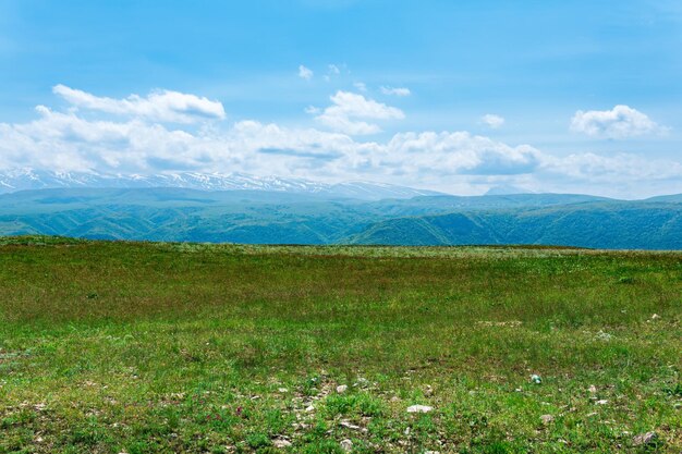 Landschaft auf einem Frühlingshochlandplateau und einer schneebedeckten Bergkette in der Ferne