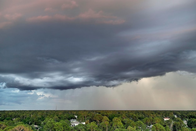 Landschaft aus dunklen ominösen Wolken, die sich bei schwerem Gewitter über dem ländlichen Stadtgebiet bei Sonnenuntergang am stürmischen Himmel bilden