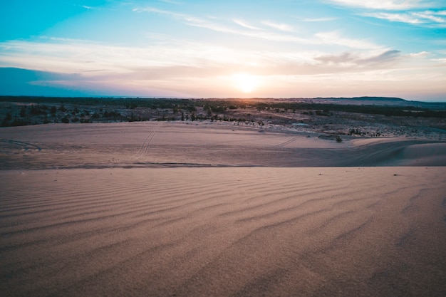 Landschaft der Sonne über Skyline in der Wüste bei White Sand Dunes Mui Ne, Vietnam. Landschaftspanorama unter malerischem buntem Himmel bei Sonnenuntergang Sonnenaufgang. Schöne Aussicht auf hellen dramatischen Himmel dunkler Boden