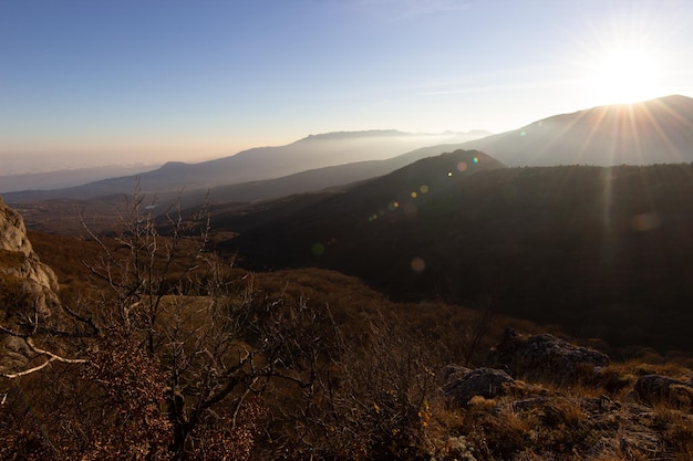 Landschaft der Sonnenuntergangssonne in den Bergen Roter Reflex von der Sonne auf den Hügeln Felsen und Bäume