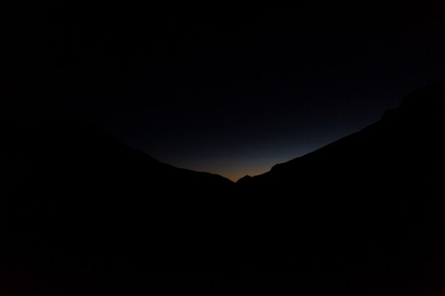 Landschaft des dunklen Schattenbildhügels in der Nacht mit einem Licht auf ihnen