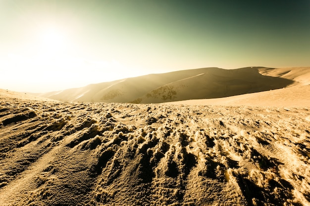 Landschaft des Schneewintertals und der Berge und der Sonne oben am klaren frostigen Wintertag. Blick auf das Winterwunderland-Naturkonzept