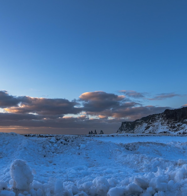 Landschaft des Strandbereichs Völlig schneebedeckter schwarzer Sandstrand mit goldenem Sonnenaufgang