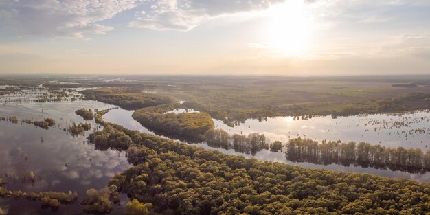 Landschaft eines kleinen Dorfes in der Nähe eines überschwemmten Flusses bei Sonnenuntergang