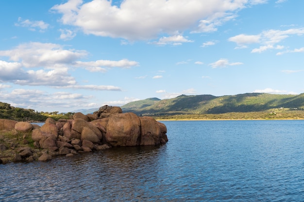 Landschaft eines Sees mit einer Nahaufnahme von Granitfelsen, die am Ufer aufgetürmt sind