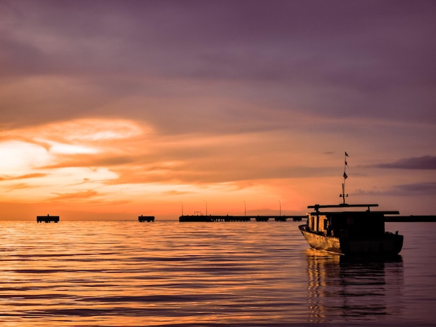 Landschaft im Freien bei Sonnenuntergang mit Fischerboot in einem Meer