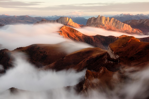 Landschaft mit alpinem Bergtal niedrigen Wolken Wald blauer Himmel Luftbild