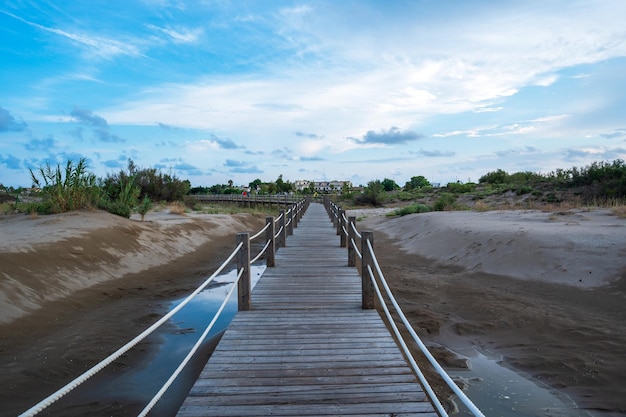 Landschaft mit Holzsteg im Sand am Strand