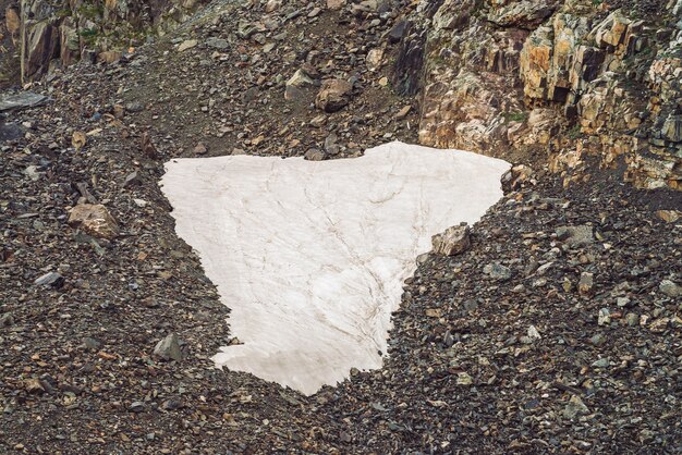 Landschaft mit kleinem Schneefeld auf Talus auf felsigem Berg