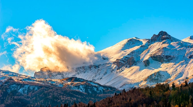 Landschaft mit schneebedeckten Berggipfeln und einer kleinen Wolke in der Nähe