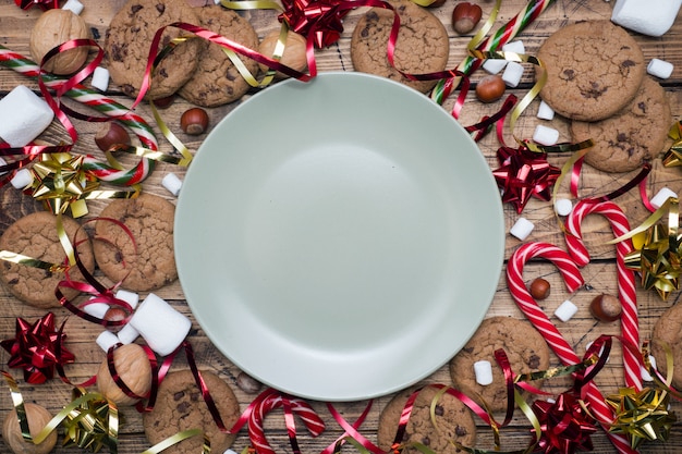 Landschaft und Eibisch des Schokoladensplitterplätzchen Weihnachtsstockkaramells rotes Goldauf hölzerner leerer Platte. copyspace Rahmen.