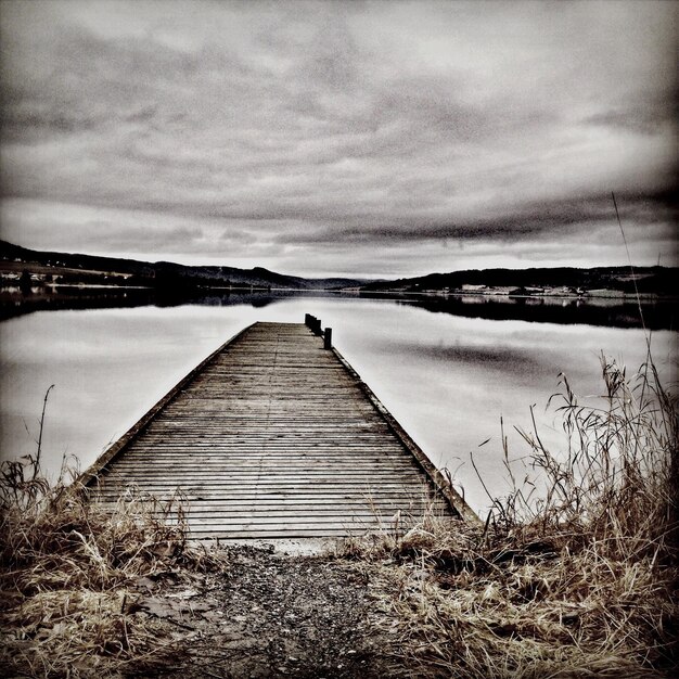 Foto landschaftliche aussicht auf den pier am see vor bewölktem himmel