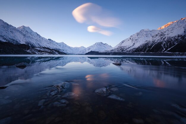 Landschaftliche Aussicht auf den See und die schneebedeckten Berge vor dem Himmel