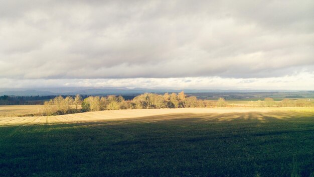 Foto landschaftliche aussicht auf ein landwirtschaftliches feld vor einem bewölkten himmel