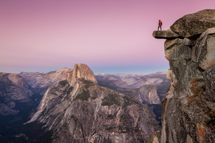 Foto landschaftliche aussicht auf felsige berge mit einem mann, der bei sonnenuntergang gegen den himmel steht