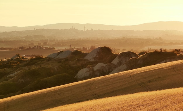 Foto landschaftliche aussicht auf toskanische lehmhügel und berge im goldenen licht siena türme im hintergrund