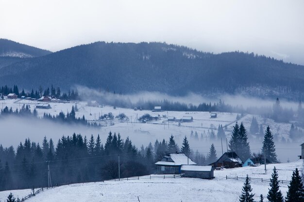 Landschaftliche Szene schneebedecktes Dorf in den Bergen neblige Morgenlandschaft