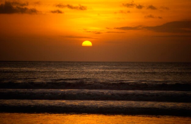 Landschaftlicher Blick auf das Meer vor orangefarbenem Himmel
