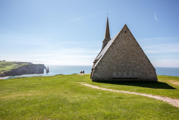 Landschaftsblick auf die felsige Küste mit alter Kirche in der Nähe der Stadt Etretat in Frankreich während des sonnigen Tages