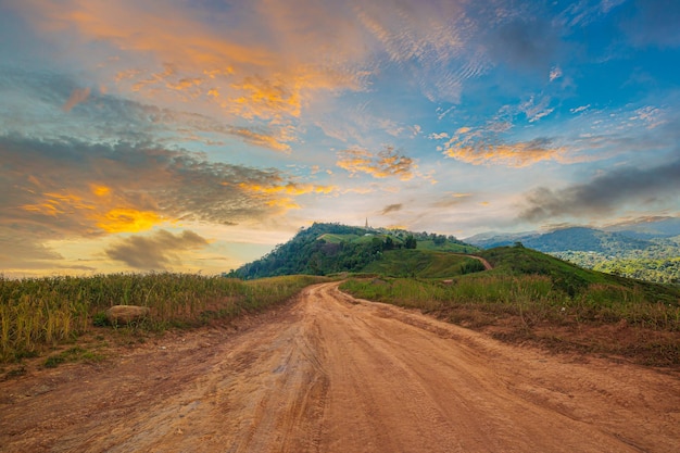 Landstraße und Berglandschaft am Abend, Straße in einem grünen Feld mit und Bergen darunter