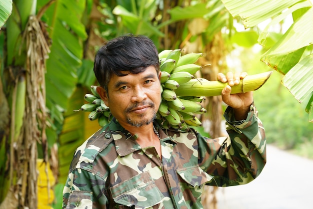 Landwirt, der von den grünen Bananen trägt