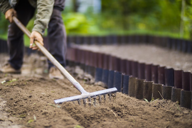 Landwirt kultiviert Land im Garten mit Handwerkzeugen Bodenlockerung Gartenkonzept Landwirtschaftliche Arbeit auf der Plantage