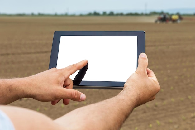 Landwirt mit Tablet-Computer im landwirtschaftlichen Anbaugebiet. Weißer Bildschirm.