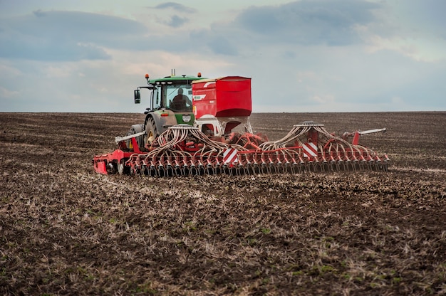 Landwirte säen und düngen mit einem John Deere 8370R Traktor mit einer POTTINGER TERRASEM c8 Sämaschine auf einem gepflügten Feld