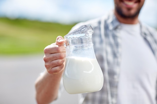 Foto landwirtschaft, landwirtschaft, menschen und molkereikonzept - mann oder bauer mit milchkrug auf dem land