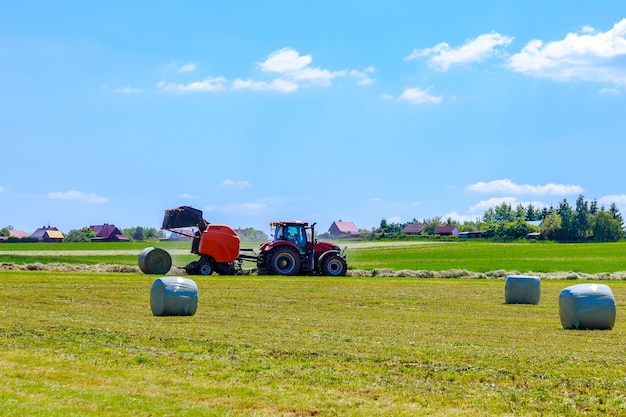 Landwirtschaftliche Ballenpresse, die einen Heuballen entlädt und gleichzeitig trockenes Weidegras für die Winterfütterung presst.