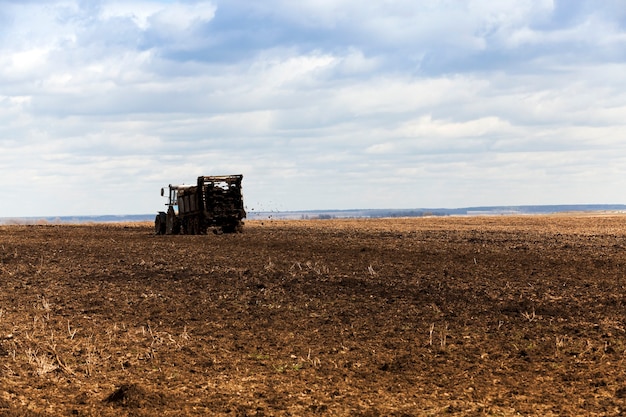 Landwirtschaftliches Feld, auf dem der alte Traktor Mist ausbreitet, um das Land zu düngen