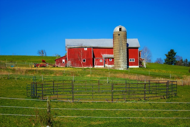 Foto landwirtschaftliches feld mit roter scheune gegen klaren blauen himmel