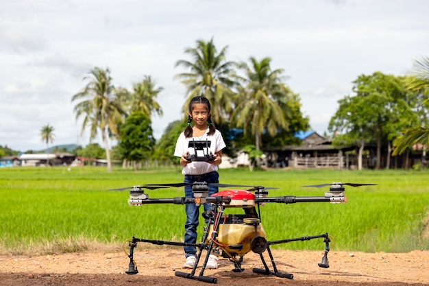 Landwirtschaftsbauerin hält Tablet, um einen Bericht über das Reislandwirtschaftsfeld, das Agrartechnologiekonzept anzuzeigen. Landwirtschaftsdrohne fliegt zu versprühtem Dünger auf den Reisfeldern.