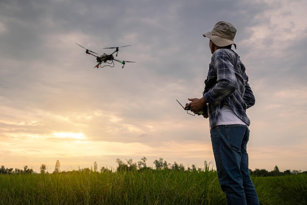 Landwirtschaftsspezialist steuert Landwirtschaftsdrohne mit Fernbedienung zum Versprühen von Düngemitteln und Pestiziden auf Reisfeldern Landwirtschaft 5g Smart Farming Intelligentes Technologiekonzept