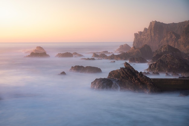 Lange Belichtung der Wellen, die auf den Felsen des Strandes Azenha de Mar in Costa Vicentina zusammenstoßen.