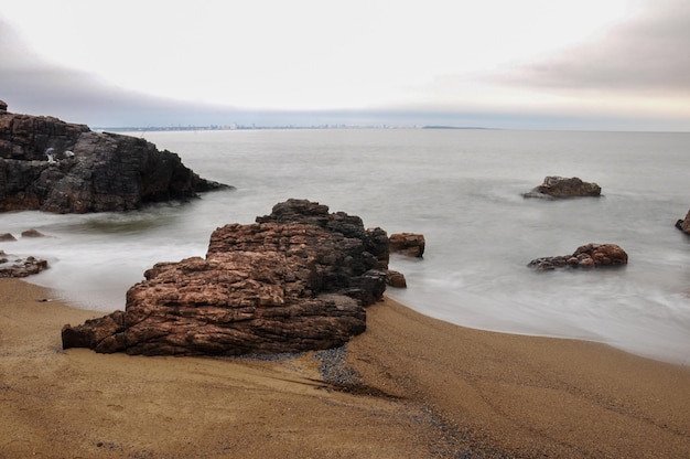 Lange Belichtung des Meeres, das einige Felsen in Mansa Beach Punta del Este trifft