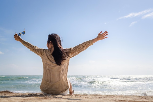 Foto lange haare asiatische frau sitzt entspannt am strand