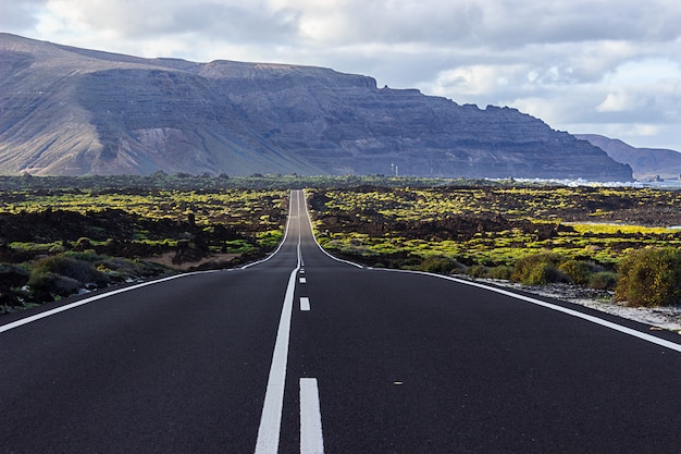 Lange Straße in die Berge mit dem Meer daneben