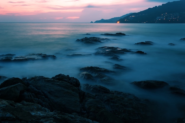 Foto langes belichtungsbild des drastischen himmelmeerblicks mit felsen im sonnenunterganglandschaftshintergrund