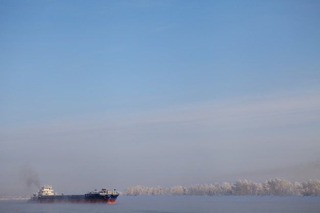 Langes Schiff, das im kalten Winter den Fluss hinuntergeht