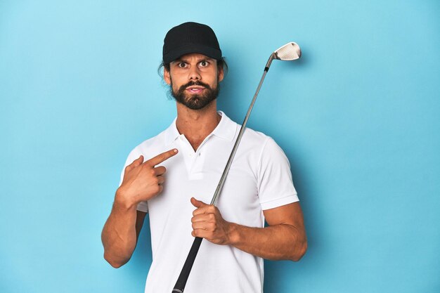 Langhaariger Golfspieler mit Club und Hut, der zur Seite zeigt