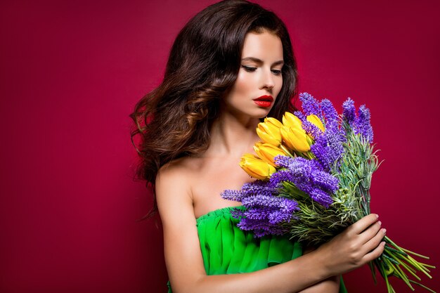 Langhaariger verlockender Brunette mit Blumenstrauß