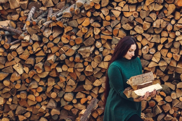 Langhaariges Mädchen hält gefaltetes Brennholz in ihren Armen