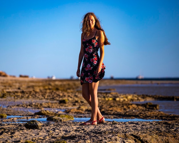 Langhaariges Mädchen im schwarzen Kleid geht am Strand von Coral Bay bei Sonnenuntergang, Strand von Westaustralien