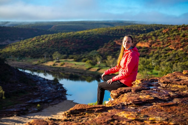 Langhaariges Mädchen sitzt auf einem Hügel auf den roten Felsen des Kalbarri-Nationalparks in Westaustralien