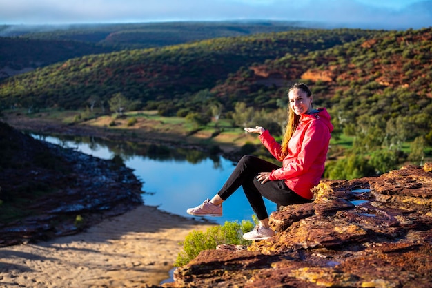 Langhaariges Mädchen sitzt auf einem Hügel auf den roten Felsen des Kalbarri-Nationalparks in Westaustralien