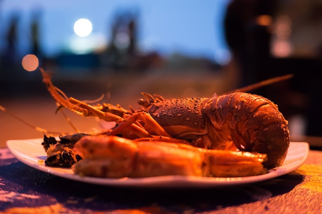 Langosta roja asada en un plato con gambas con fondo borroso. Mariscos exóticos en el restaurante