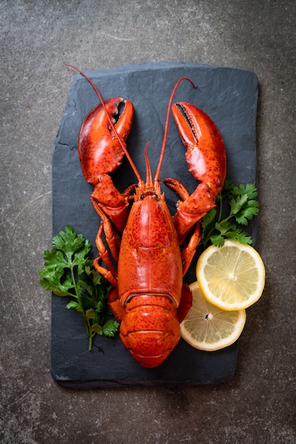 Langosta con verduras y limón sobre placa de pizarra negra