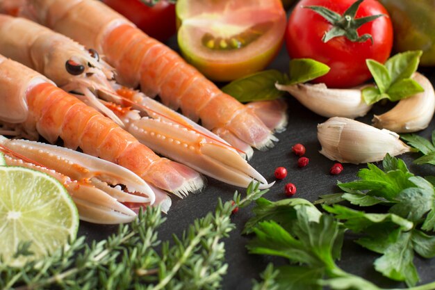 Langostinos crudos con verduras y hierbas en la mesa oscura