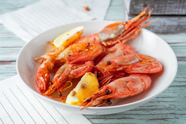 Langostinos gigantes con rodajas de limón servido en plato blanco